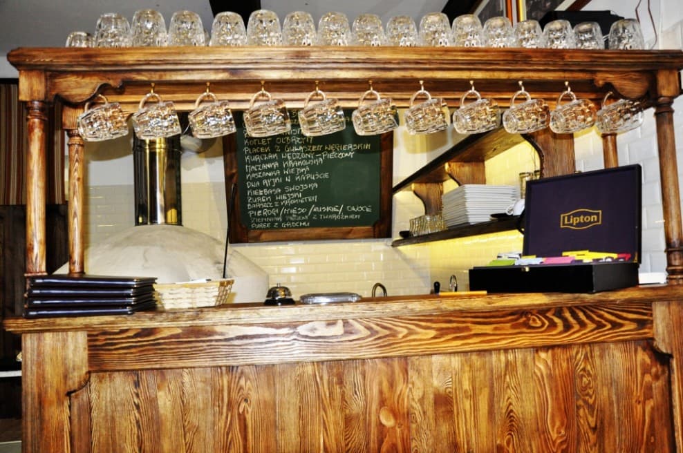 Drewniany bar z wiszącymi szklanymi kuflami